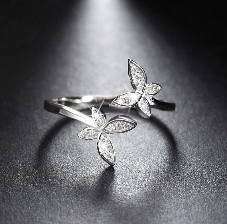 Silver butterfly-shaped rings on a dark surface
