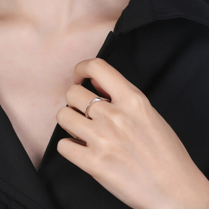 Hand wearing a silver ring on a black background