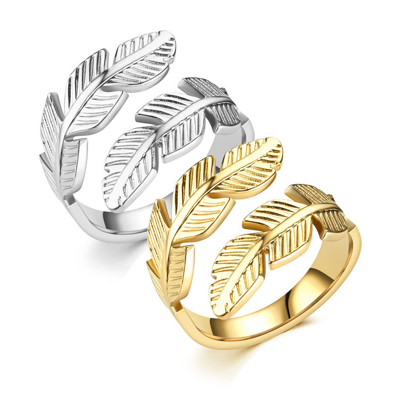 Two feather-shaped rings, one silver and one gold, on a white background.