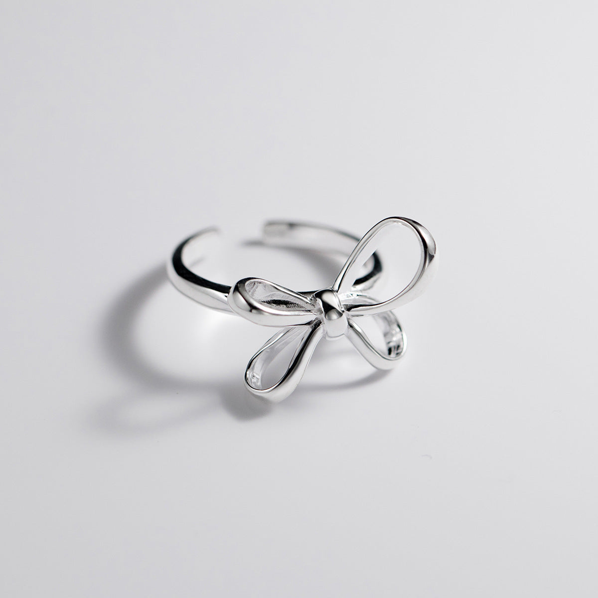 Silver bow-shaped ring on a light gray background