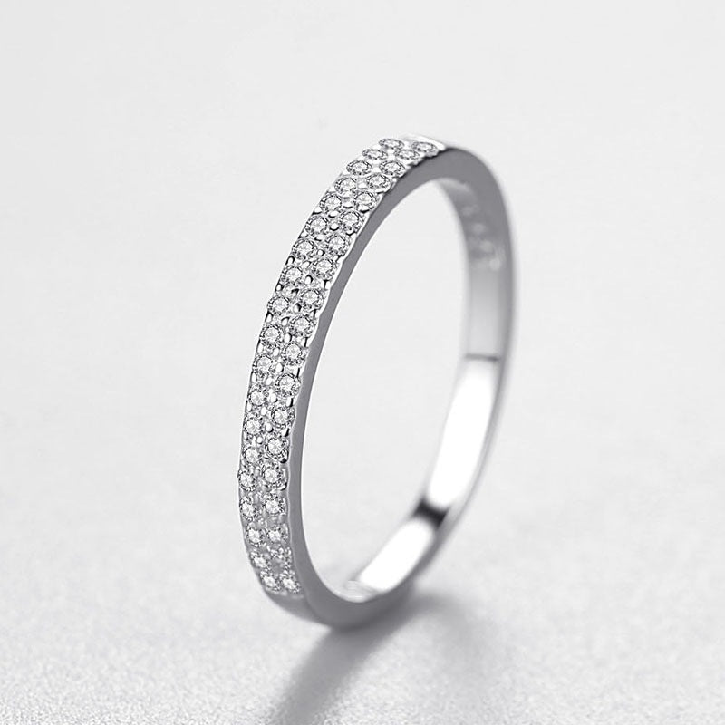 Silver ring with small diamonds on a light gray background