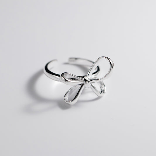 Silver bow-shaped ring on a light gray background